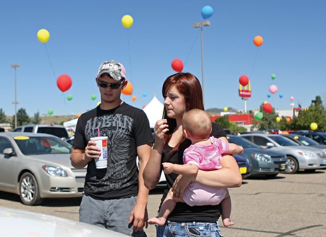 Tim Turner, left, and his wife, Rachelle, holding their 7-month-old daughter, Abigail, look at a sports utility vehicle during a vehicle tent sale Tuesday in the Kmart parking lot. The sale features used vehicles from Grand Valley Auto in Grand Junction. Local dealers say organizers of such events have no accountability to customers once they’ve made a sale.