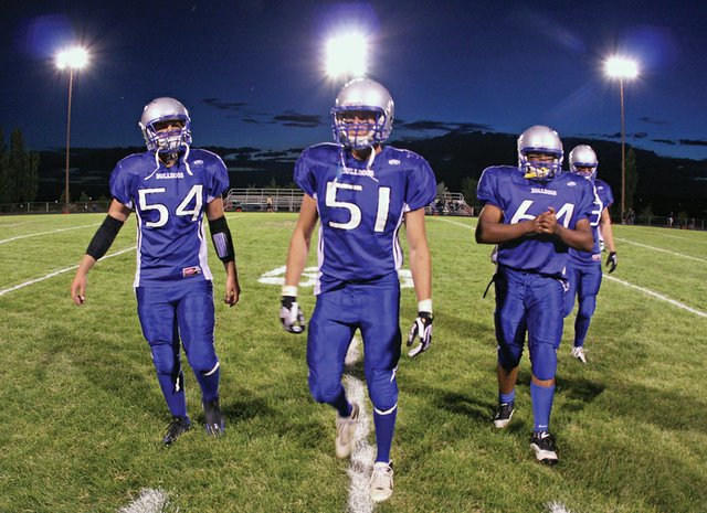 Moffat County High School football team captains, Angelo “Hodge” Raftopoulos, left, C.J. Walt, middle left, Casey Martin, middle right, and Brady Conner, right, walk back to the sideline at halftime of the season opener against Evergreen High School on Friday at the Bulldog Proving Grounds. The Bulldogs fell to the Cougars, 26-22.