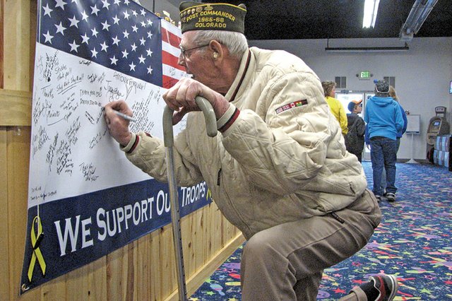U.S. Marine Corps veteran Alvin Lawton, who served in Korea from 1952 to 1954, signs his name to a banner Saturday at Thunder Rolls Bowling Center in Craig. The banner is in support of U.S. troops. During the past month, Thunder Rolls has raised more than $2,500 for the Bowlers to Veterans link, an organization that provides support to former and active servicemen and women.