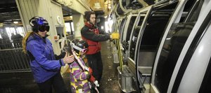 Steamboat Ski and Resort Corp. lift operator Kevin Reid helps Steamboat resident Kristy Fox and her nine-year-old daughter Lily load a gondola car Friday. Ski Corp. officials spent the day fielding phone calls about security measures.