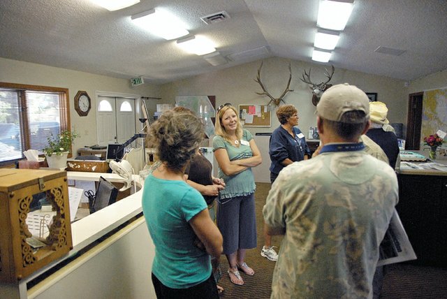 Christina Oxley, center, executive director of the Craig Chamber of Commerce and its Moffat County Visitor Center, converses with community members and chamber board members Thursday in the Craig Chamber of Commerce during the organization’s 65th anniversary celebration. Oxley said as the chamber looks to the future, she and the chamber’s staff and board plan to continue to increase visibility on the Internet.