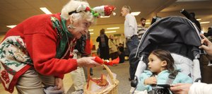 Steamboat Springs Chamber Resort Association visitor information specialist Donna Hellyer offers a candy cane to 2-year-old India Castellino, of Los Angeles, on Friday at Yampa Valley Regional Airport. Officials say passenger numbers at the airport this ski season are up more than 5 percent from last year.
