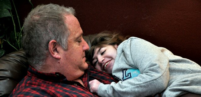 Katelynn Hildebrandt, 16, smiles at her father, Todd, as he prepares to feed her early one morning in mid-February. Because Katelynn is legally blind and deaf and cannot speak, her parents may never know how much of the world she perceives or understands, yet she expresses her affection for them during the most routine acts of the day.