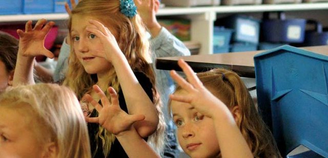 Sunset Elementary School first-graders Paityn Cox, left, and Grace Baker, right, hold up their hands to show how big a plant the size of a dinner plate might be during a webinar Tuesday morning in Cheryl Arnett’s class. Her students are learning about water through an initiative that connects them with students in Brazil, India, Saudi Arabia and Taiwan.