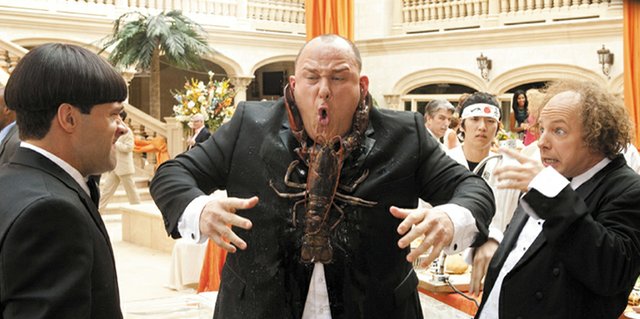 Curly (Will Sasso) finds himself on the wrong end of a seafood dinner at a high society function, much to the amusement of pals Moe (Chris Diamantopoulos) and Larry (Sean Hayes) in “The Three Stooges.” The movie is a recreation of the classic comedy team, focusing on the Stooges as they set out to save their childhood orphanage.