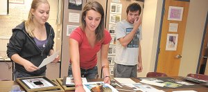 Photography students Dani Perry, right, and Haley Orton look through images while preparing for First Friday Artwalk. The students’ photographs will be displayed at City Cafe during May.