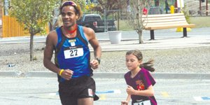 Roberto Mandje helps a young participant across the finish line Saturday at the 2012 Spirit Challenge. Mandje was in town between training for the 1,500-meter event at the 2012 London Olympics.