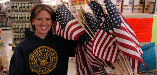 Mandy More shows off the patriotic setup of miniature American flags on sale at Murdoch’s. More, 30, is an assistant manager at the supply store and will be paying tribute to members of the military today, including her grandparents and her sister, who recently finished a tour of duty with the U.S. Navy.