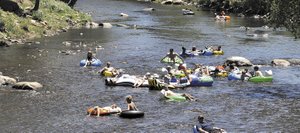 Clusters of tubers float down the Yampa River on Sunday near the Fifth Street Bridge. The river was barely flowing above 100 cubic feet per second Sunday afternoon, and its decline is expected to continue as hot dry weather is in the forecast again this week.
