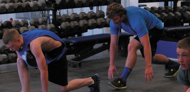 Moffat County High School students Owen Nichols (left) and Michael Samuelson participate in the “reverse lunge” to help stretch and warm up for the BEAST training session Thursday. BEAST is being taught by MCHS graduate and Colorado Mesa University strength and conditioning coach Daniel Linsacum with the aim of education athletes about proper strength training.