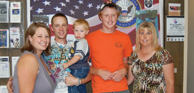 Jordan Bailey, second from left, stands proudly with wife, Kacie, son, Kaeden, cousin Wyatt Oberwitte and aunt Kathy Bailey beneath a banner made especially for him. Jordan recently returned from a tour of duty with the U.S. Navy and was greeted by friends and family at a surprise party Friday afternoon.