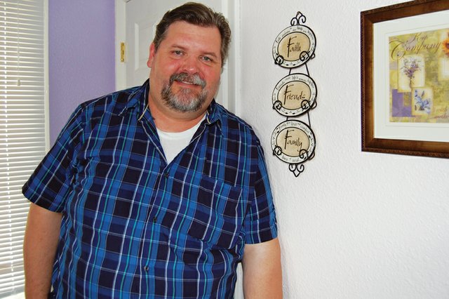 Bruce Cummings leans against a wall decoration emphasizing faith, friends and family in the offices at Advocates-Crisis Support Services. Cummings, who has been involved with the organization for five years, is starting a new program called Men’s Voices Against Violence and hosted the first meeting last night.