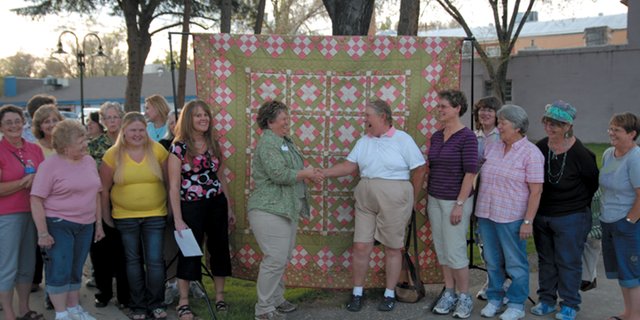 Lorrae Moon, center left, shakes hands with Mary Nelson, of the Yampa Valley Ladies Golf Association, last spring while presenting the quilt as a donation to the association. The quilt garnered $1,266 in the form of donations for the Moffat County Cancer Society this year. The ladies golf association accepted donations for chances to win the quilt.