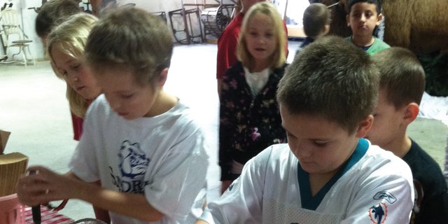 Tanner Zimmerman, left, a third grader at Sandrock Elementary School, and his twin Tucker Zimmerman take their turn smashing apples for applesauce at the Wyman Museum Monday afternoon. Sandrock third graders went on the field trip as part of their pioneer days studies, meeting state standards for history.