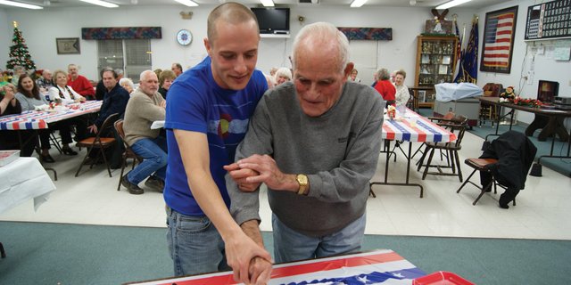 Travis Doolin, a Craig local and Chief Petty Officer in the United States Navy, left, the youngest member at the VFW Christmas dinner and Gaylord Fliece, the oldest member of the VFW, who also served in the Navy, cut the cake Monday night at the party. Taking a page from Marine Corps tradition, the two cut the cake together. Doolin was the guest of honor at the dinner.