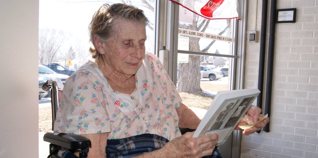 Sandrock Ridge Care & Rehab resident Anna Mae Fleming Adams sits in the sun Wednesday while looking at the book she wrote, "The Snake River From Three Forks to Columbine." The book contains Adams' memories and those of others who lived in the hills. Sandrock Ridge is hosting a book signing and reception for Adams at 2 p.m. Friday.