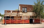 Fawna Odom, owner of the HiWay Bar, walks on scaffolding Monday to try to make out an old sign painted on the building.