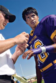 LSRV football assistant coach Jesse Herold, left, tapes up the arm of freshman Manuel Quinteros shortly before the game against visiting Hanna Elk Mountain Medicine Bow Junior Senior High School. The Rattlers lost, 68-28.