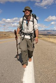 Eric Sheets walks down the white line Friday afternoon on Colorado Highway 13 north of Craig. Walking on the painted line is easier for Sheets' bare feet than the tough asphalt road.