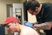 Jimmy Clark gives Tucker Vestal, 18, of Hayden, his first tattoo Thursday at Liquid Flesh Tattoo. Vestal is a senior at Hayden High School and described the process as a different kind of pain than he had felt before.