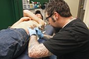 Jimmy Clark works on adding wind bars to accompany Justin Donnel’s stars tattooed on his side Thursday at Liquid Flesh. Donnel had Clark do two of the three pieces on his body and said he will never go to anyone else for tattoo work.
