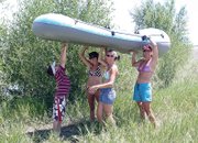 Nathan Baker, 10, left, helps Heather Vallem, middle left, Karra Juergens, middle right, and his mom, Julie Baker, carry a raft to the water Tuesday just west of Pebble Beach near Yampa Valley Golf Course.