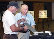 Ken Bergstron, left, drops his ballot in the box with the help of election judge Oscar King on Tuesday at the voting center at Centennial Mall. King has helped with local elections for more than 10 years and said he enjoys being part of the process.