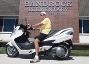 Don Riley poses for a portrait on his Suzuki Burgman 400 cubic centimeter scooter Wednesday in front of Sandrock Elementary School. Riley will act as interim principal while Sandrock principal Kamisha Siminoe is on maternity leave later this year.