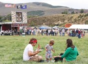 Zach Bergstrom, left, his 16-month-old child, Lexington, and his wife, Stephanie, sit in the grass while eating during the Colorado BBQ Championship on Saturday at the Wyman Museum. More than 30 teams from around the country competed in the Kansas City BBQ Association-sanctioned event.