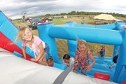 Madison Laman, left, 6, and her sister, Kassadi, 7, climb up the bouncy wall during the Colorado BBQ Championship on Saturday at Wyman Museum. There was also a hay-maze, face-painting, camel rides, fishing pool and a create-your-own-BBQ-sauce station to entertain the children.