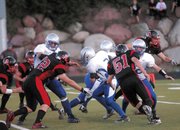 Mason Updike, center, runs through a wall of Aspen defenders Friday. MCHS would be unable to catch the high-flying Skiers, and fell, 46-13.