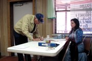James Cooper signs in at the Hamilton Community Center on Tuesday as election judge Vickie Molzahn looks on. Molzahn said the average voter turnout for Hamilton is 30. By noon, Molzahn said the turnout was on track to exceed the average.