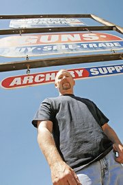 Jeff Knights stands Friday under the sign for Northwest Pawn Shop, a business he has owned for six years. The pawn shop functions as a credit card, of sorts, for people who otherwise couldn’t get credit.