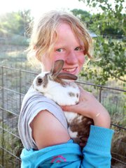 Emma Balstad holds Bucky on her shoulder July 20 at her home in Maybell. Emma said she hopes to be an animal breeder when she grows up and that breeding her rabbits in 4-H is teaching her about the trade.