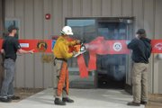 Kenny Lovell saws through a wooden ceremonial ribbon Tuesday morning at the newly constructed facility for the Craig Interagency Hotshots firefighters. The 7,000-square-foot building has been in the works since the Hotshots crew began in Craig in 2001, with construction beginning in August 2011. The crew hosted an open house following the ceremony, allowing the public to view the new building, which includes training rooms, a fitness area, a vehicle bay and more.