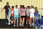 Dave Pressgrove, a coach for the Moffat County High School varsity track and field team, demonstrates the hand-off for the baton used in the relay to kids at a session of the Moffat County Youth Track program. More than 140 children have attended the program in recent weeks.
