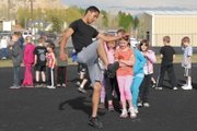 Moffat County High School senior Johnny Landa shows the proper foot placement used in the high jump to a group of young track students at Thursday’s practice session for the Moffat County Youth Track program. Landa was one of many MCHS varsity track team members who, along with other volunteers, are helping prepare participants in kindergarten through sixth-grade for the program’s May 14 track meet.