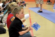 Aaron Colby, a Sunset Elementary School kindergartener, holds an Australian paper flag Monday during a kickoff to the school’s Olympic games in the school gym. Each class has adopted a different country for the two-week project, and many teachers are using the mock Olympiad to teach students about cultures and customs in other countries.