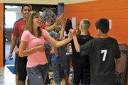 Moffat County High School track athletes Adrie Camp, foreground, and Miguel Molina, give high-fives to Sunset Elementary School students as they file out of the school gym Monday after an Olympic torch lighting ceremony. Molina, Camp, and fellow track athlete Garrett Spears attended the ceremony to help launch Sunset Elementary School’s mock Olympic games.