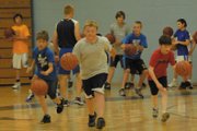 Boys from fourth through eighth grade dribble down the court to work on ball-handling skills. The Moffat County High School hosted a basketball camp Monday through today focusing on improving fundamentals. In the background, incoming MCHS sophomore Tyler Davis gets the next group of campers ready.