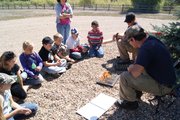 Part of an overnight outdoor education experience, fifth grade students of East and Sunset Elementary watch a fire simulation by firefighters Hawk Fick, front, and Alex Farinetti of the Craig Bureau of Land Management. Fick and Farinetti lit matches on a board, representing trees in a forrest to demonstrate how quickly a fire can spread, considering factors such as wind and slope.