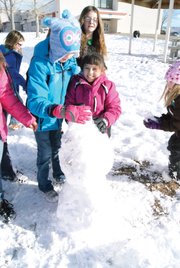 Ridgeview fourth grader McKinley Winkler, left, helps third grader Sofia Lopez build a snowman Tuesday during an afternoon recess. Students were excited to play in the snow after the huge dump the day before.