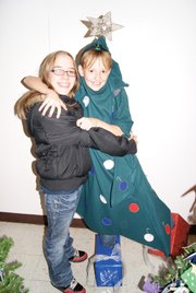 Sara Barrientez, left, a ninth grader at Moffat County High School, hugs seventh grader Kathryn Currie in her christmas tree costume Thursday night at the Festival of Trees. "I'm a tree hugger," Barrientez joked.